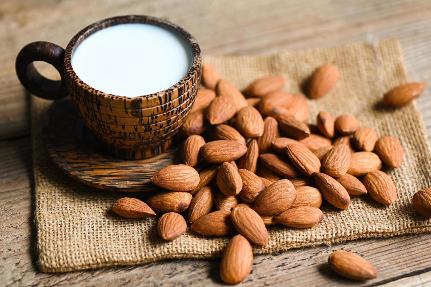 Almond milk and Almonds nuts on on sack background, Delicious sweet almonds on the table, roasted almond nut for healthy food and snack photo