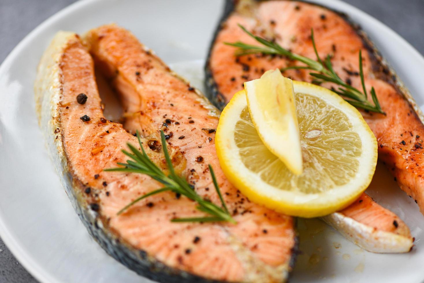 Grilled salmon steak with herbs and spices rosemary on plate background - Close up cooked salmon fish fillet steak seafood photo