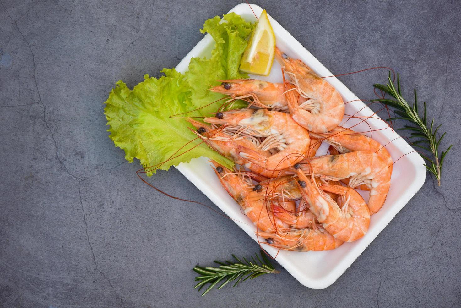 gambas frescas en una bandeja de plástico con especias de limón y hierbas, gambas hervidas cocinando comida en el restaurante de marisco foto