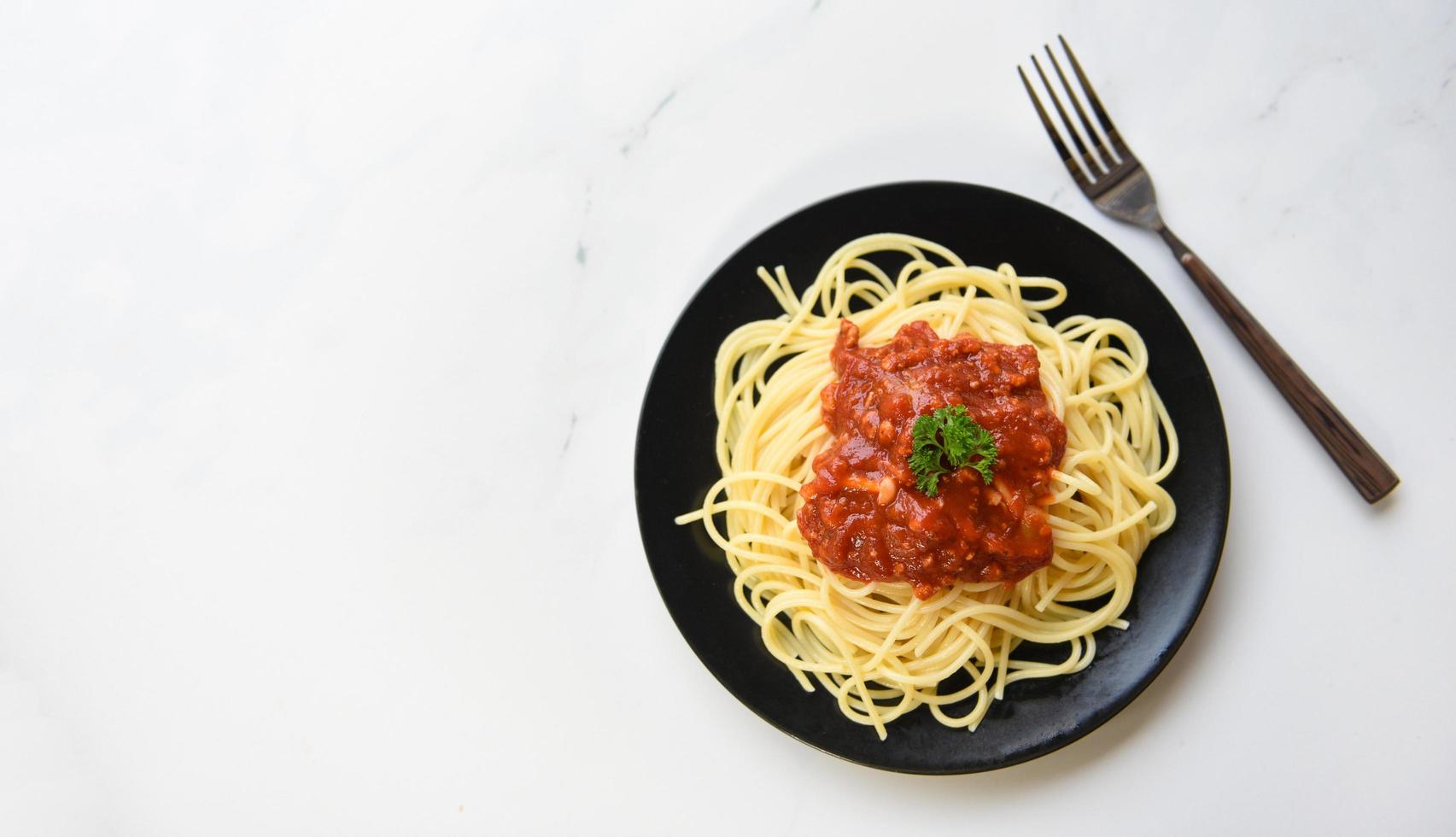 espaguetis a la boloñesa, vista superior: pasta italiana de espaguetis servida en un plato negro con salsa de tomate y perejil en el restaurante comida italiana y concepto de menú foto