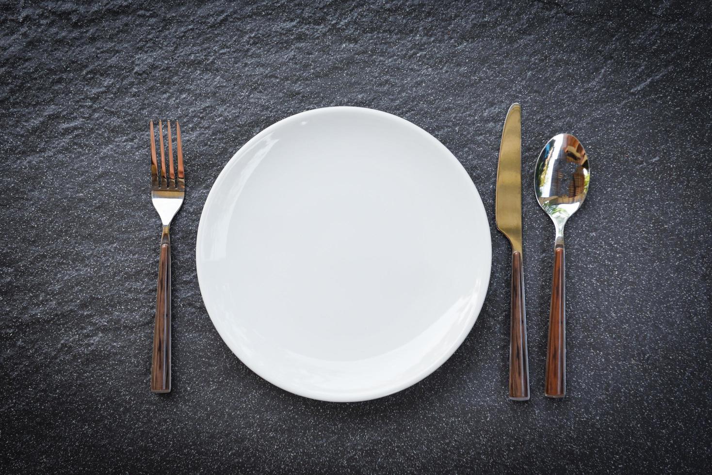 Coloque la comida en la mesa con un juego de platos blancos sobre manteles o una servilleta en la cena, un plato vacío, una cuchara, un tenedor y un cuchillo en la mesa. foto