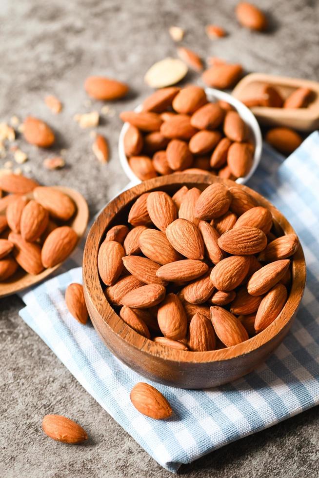 Almonds nuts on wooden bowl and dark background, Delicious sweet almonds on the table, roasted almond nut for healthy food and snack photo