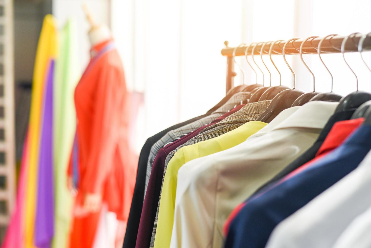 ropa de moda de mujer de diferentes colores ropa en perchas en la sala de exposición - ropa colgada traje colorido o estante de armario foto