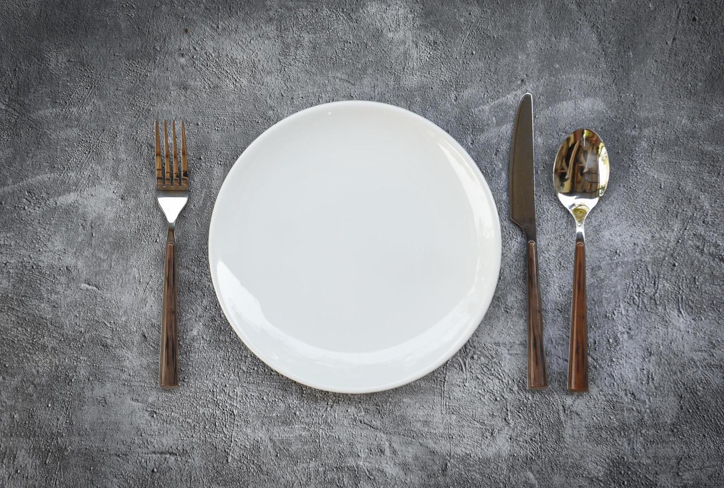 Coloque la comida en la mesa con un juego de platos blancos sobre manteles o una servilleta en la cena, un plato vacío, una cuchara, un tenedor y un cuchillo en la mesa. foto