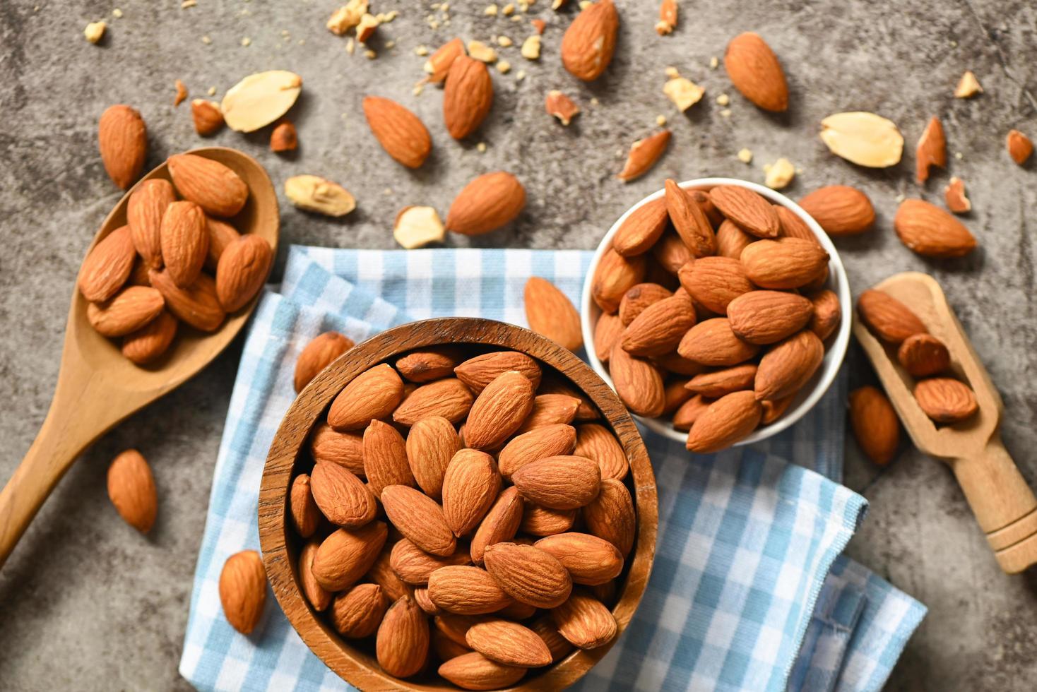 nueces de almendras en un tazón de madera y fondo oscuro, deliciosas almendras dulces en la mesa, nuez de almendra tostada para una comida saludable y un refrigerio foto