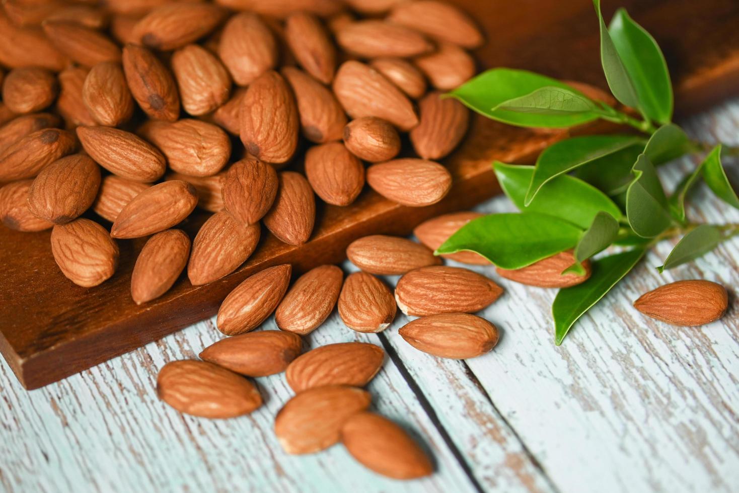 Almonds nuts on wooden background white green leaf , Delicious sweet almonds on the table, roasted almond nut for healthy food and snack photo