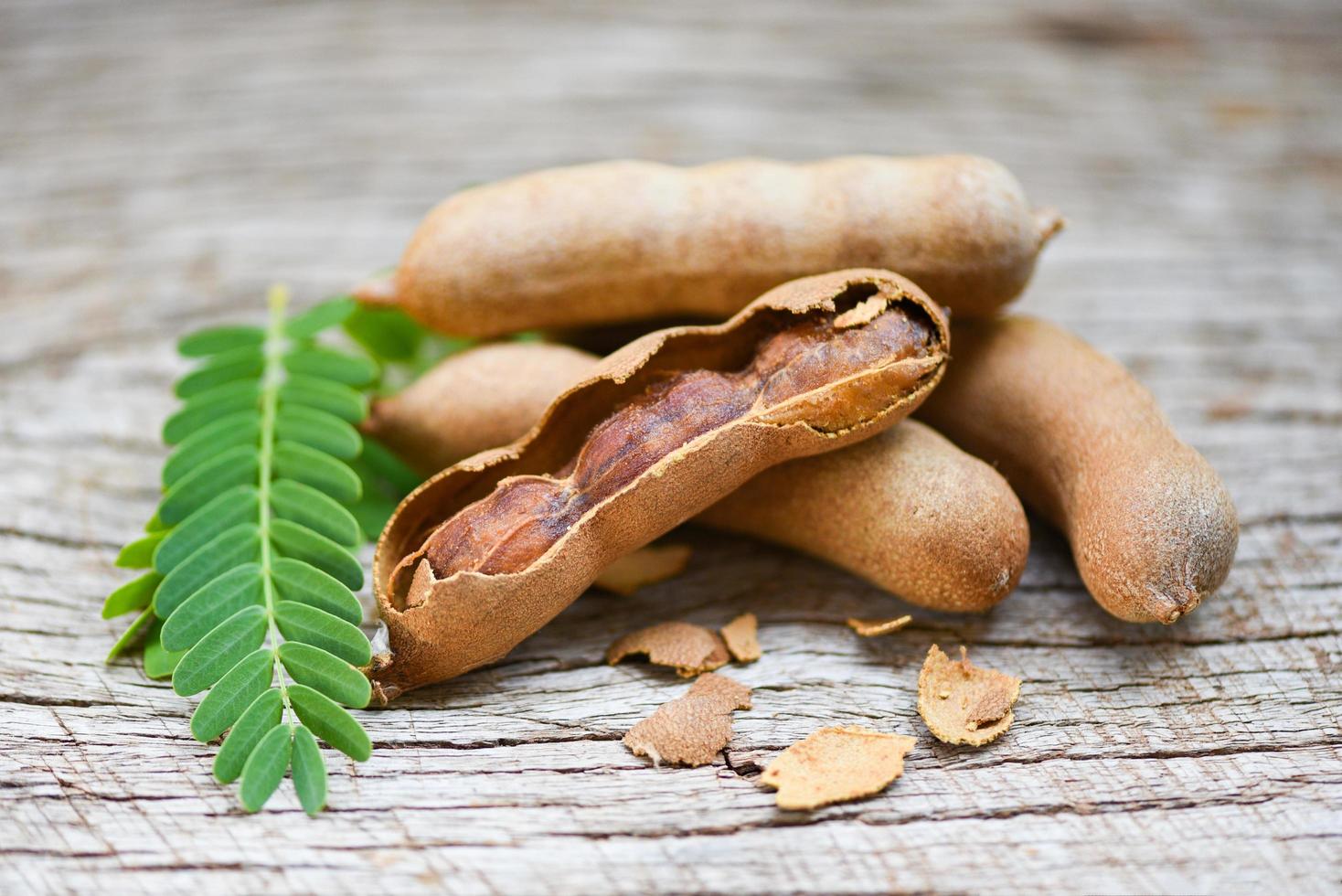 Sweet tamarind on wooden background - fresh tamarind fruits and leaves photo