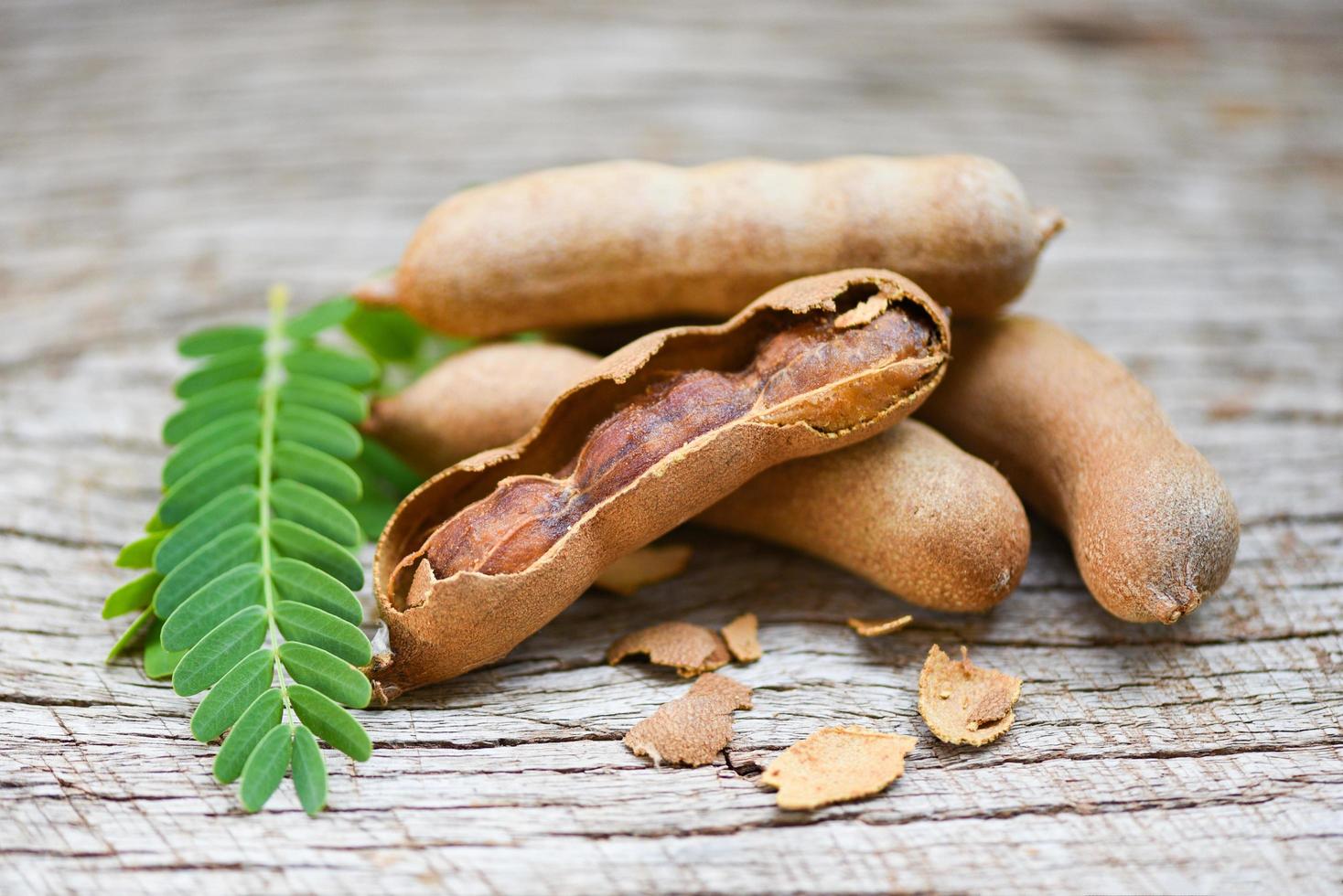 tamarindo dulce sobre fondo de madera - frutas y hojas frescas de tamarindo foto