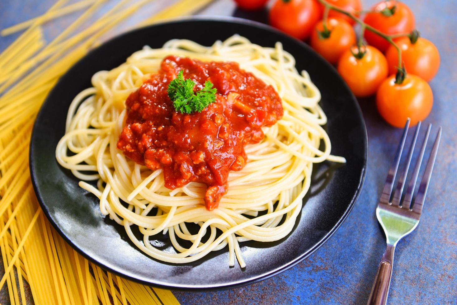 espaguetis a la boloñesa espaguetis pasta italiana servida en un plato negro con tomate y perejil en el restaurante comida italiana y menú foto