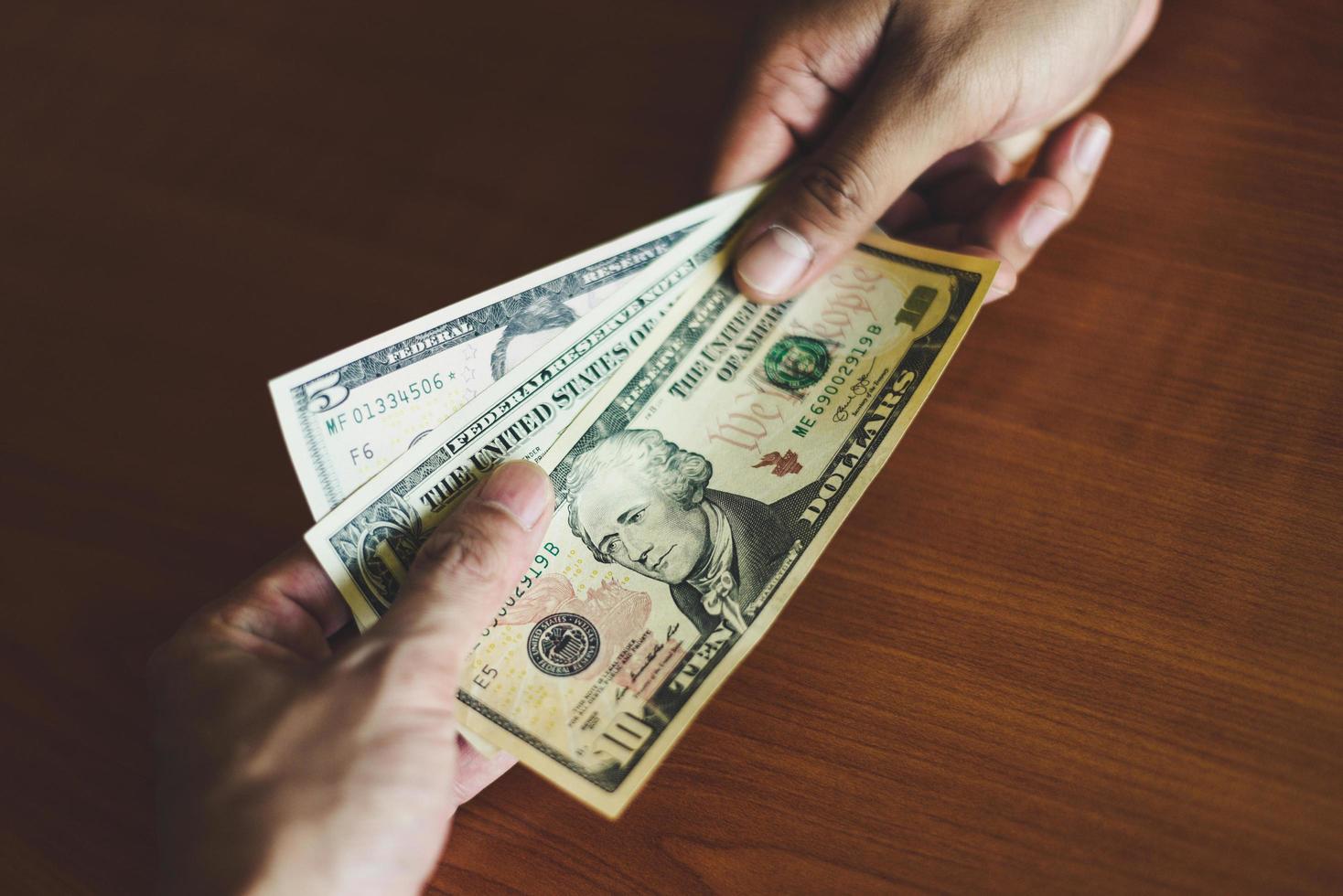 Business man give money bribe concept - person hands man giving money on wooden table background pay cash on delivery pay to receive money photo