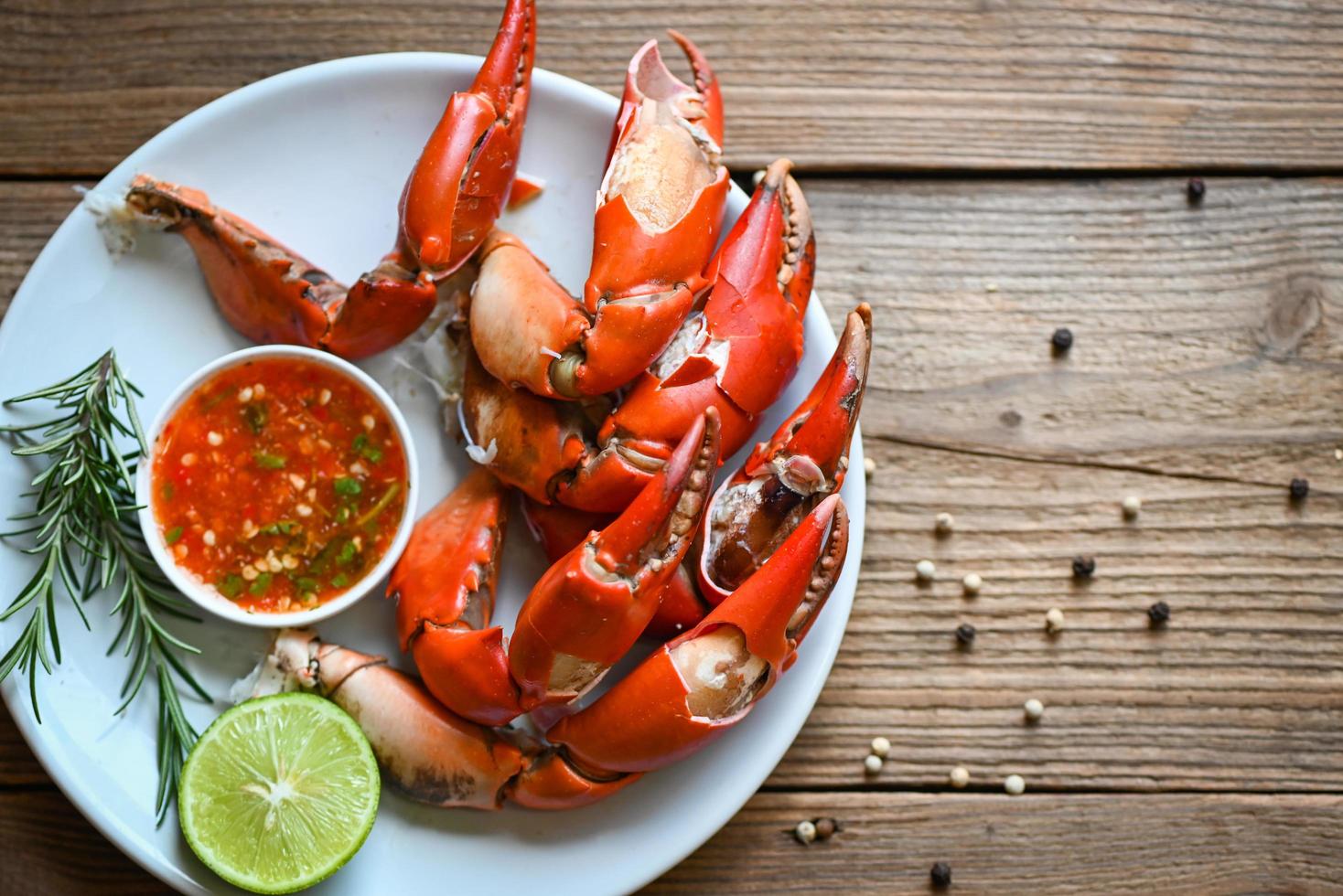 claw crab cooking food seafood plate with pepper herbs spices lemon lime salad, fresh crab on white plate seafood sauce, boiled or steamed crab red in the restaurant photo