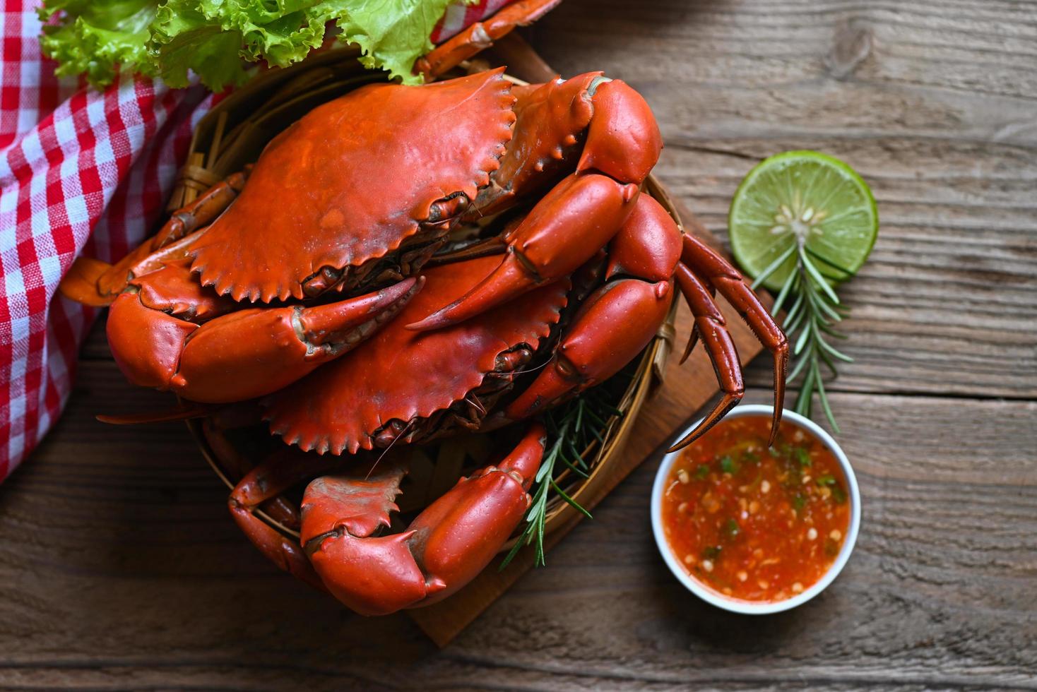 fresh crab on wooden and seafood sauce, seafood plate with herbs spices rosemary lemon lime salad lettuce vegetable, crab cooking food boiled or steamed crab red in the restaurant photo