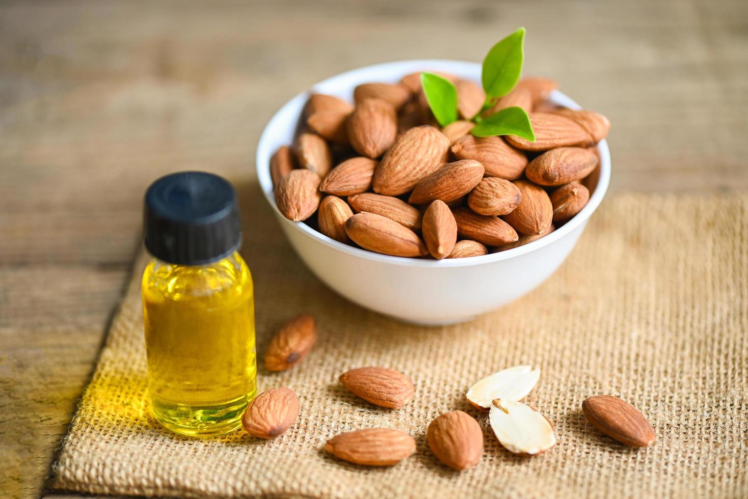 aceite de almendras y nueces de almendras en el bol, delicioso aceite de almendras dulces en botella de vidrio, nueces de almendras tostadas para alimentos saludables y aceites vegetales orgánicos para cocinar o spa foto