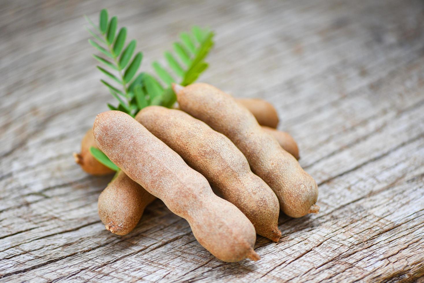 Sweet tamarind on wooden background - fresh tamarind fruits and leaves photo