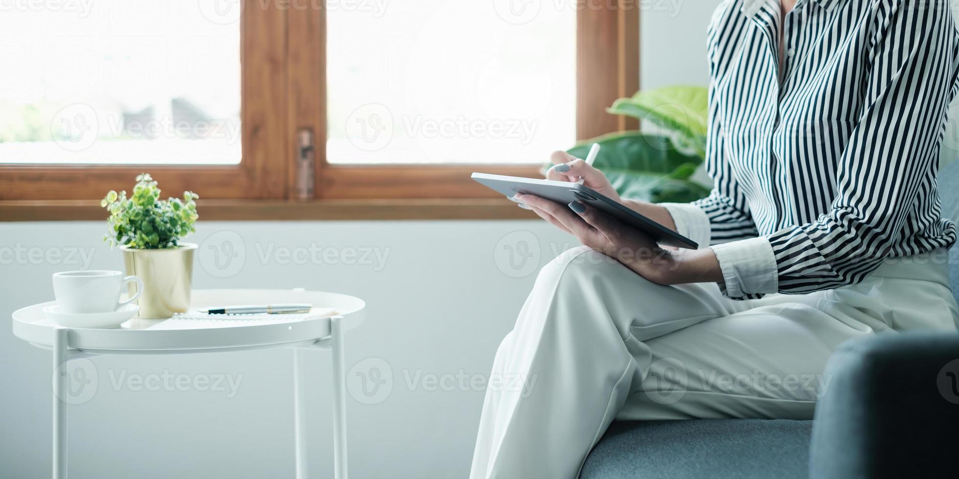 Woman enjoy with content social media application on digital tablet sitting on sofa at home. photo