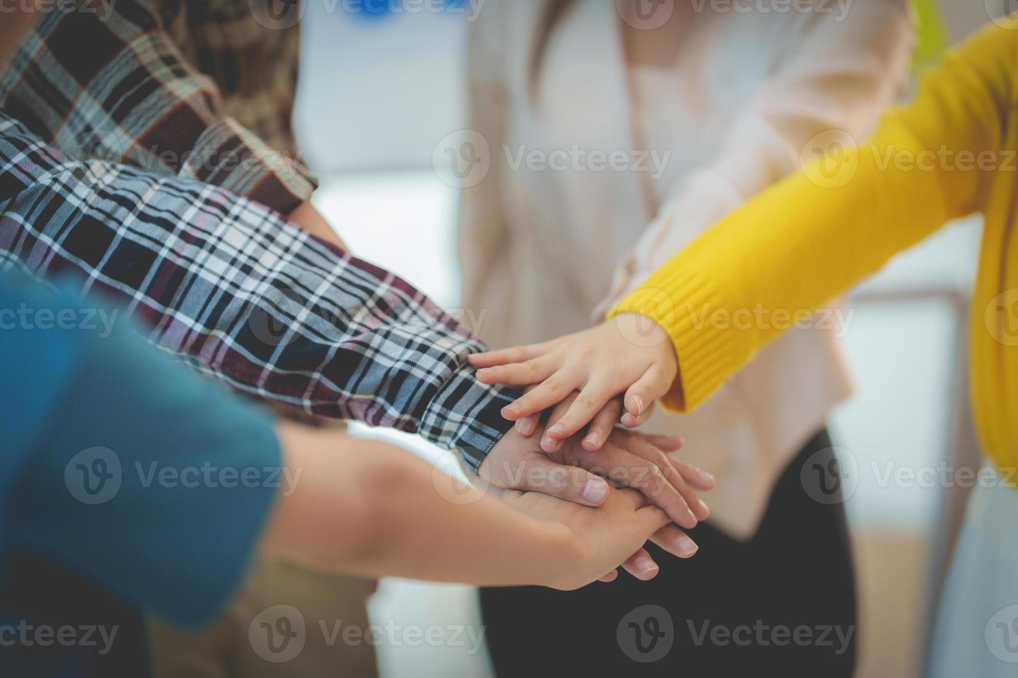 Group of Multiracial people putting their hands working together showing oneness symbol. photo