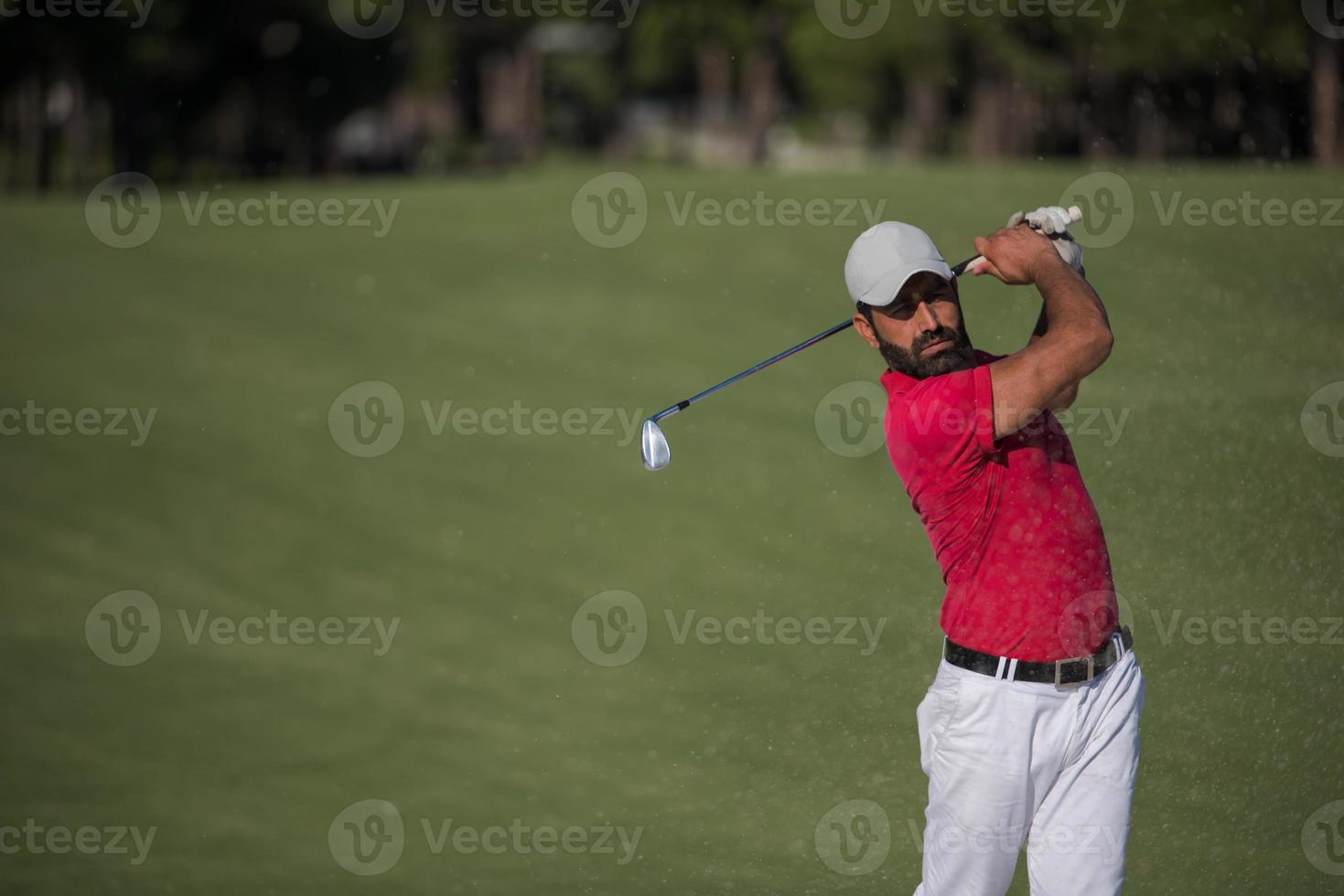 golfer hitting a sand bunker shot photo