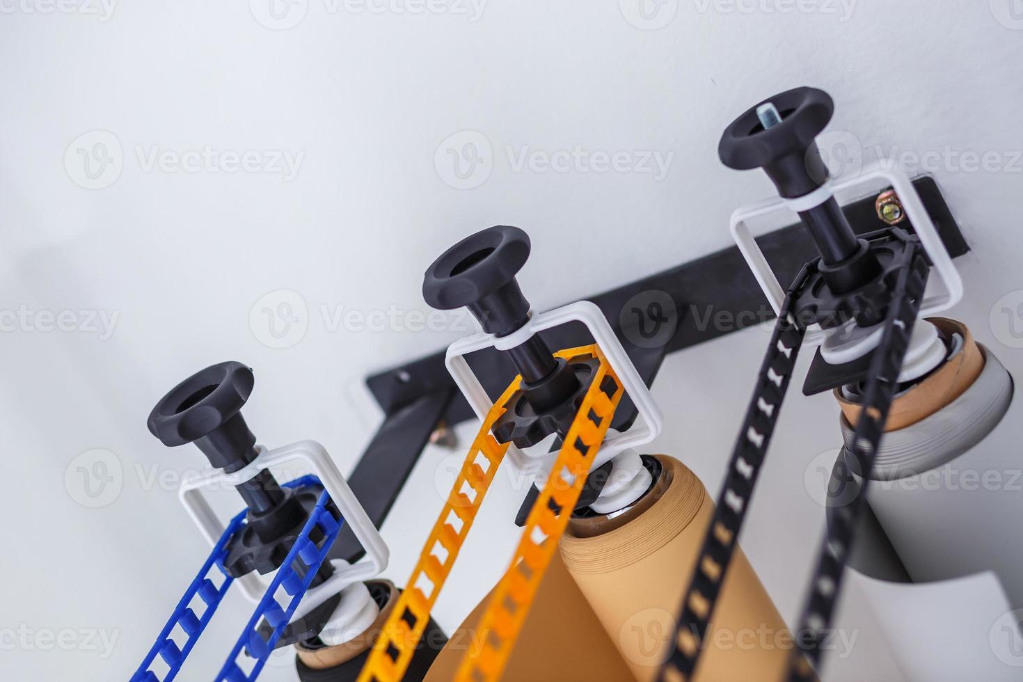 mounting manual support system for photo backdrops in modern studio. Rolls of colorful paper backgrounds for photo studio hang on the wall