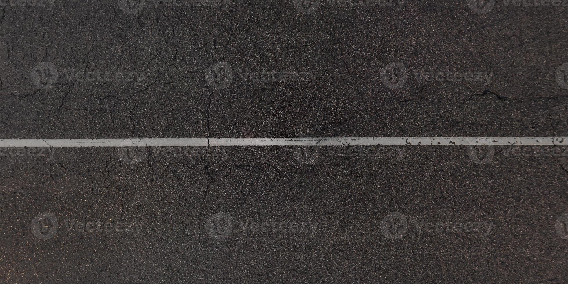 view from above on surface texture of old asphalt road with cracks photo