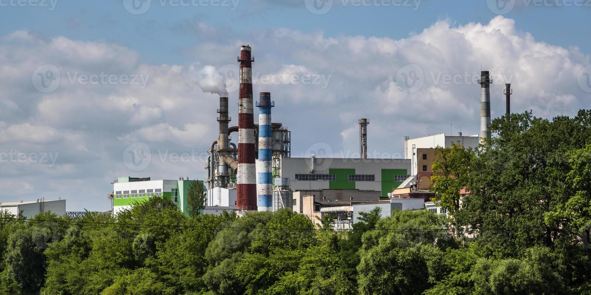 pipes of woodworking enterprise plant sawmill near river. Air pollution concept. Industrial landscape environmental pollution waste of thermal power plant photo