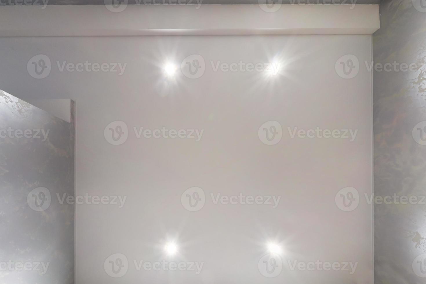 suspended ceiling with halogen spots lamps and drywall construction in empty room in apartment or house. Stretch ceiling white and complex shape. photo