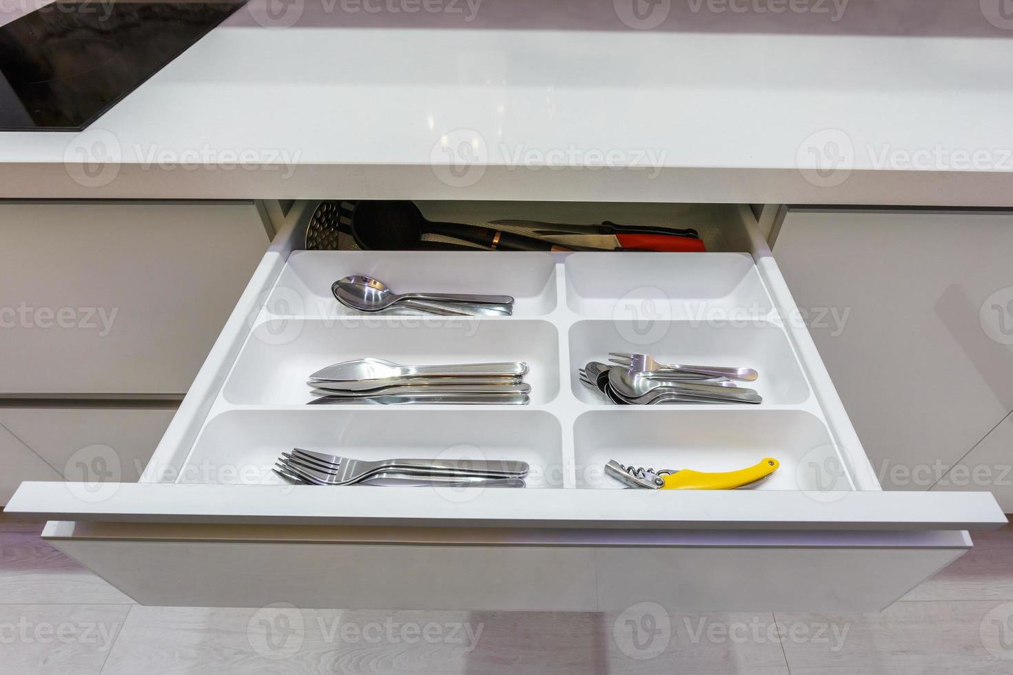 set of knives, forks and  spoons on the shelf in the kitchen cabinet photo