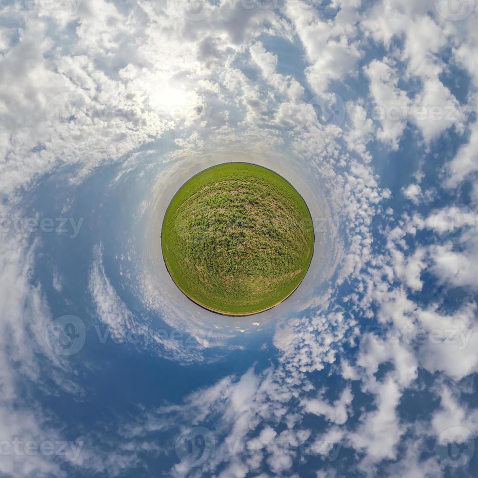 green tiny planet in blue sky with beautiful clouds. Transformation of spherical panorama 360 degrees. Spherical abstract aerial view. Curvature of space. photo