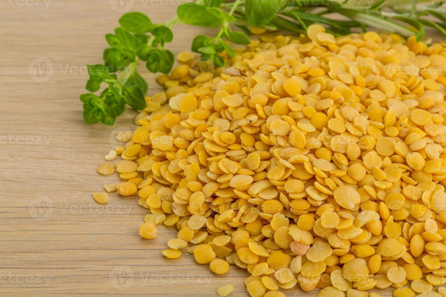 Raw yellow lentils on wooden background photo