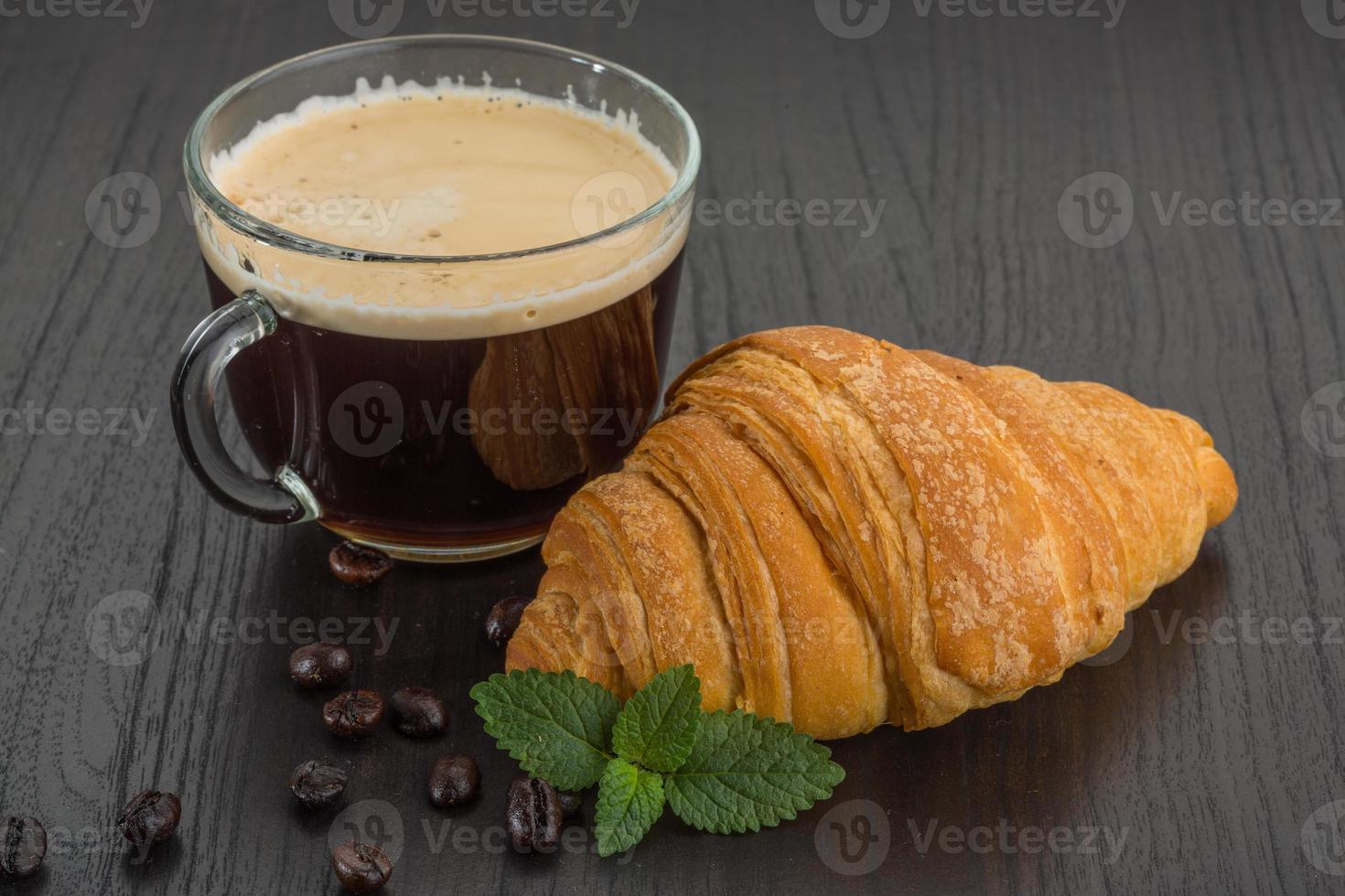Coffee with croissant on wooden background photo