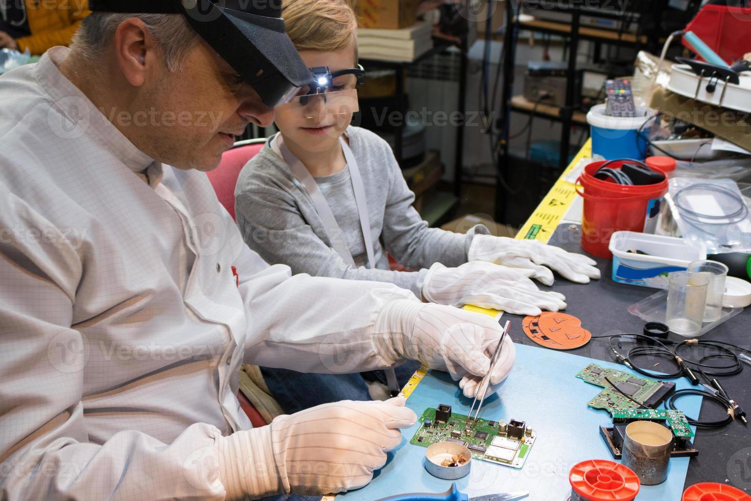 IT technician teaching little boy to repair mother board in tech laboratory. photo