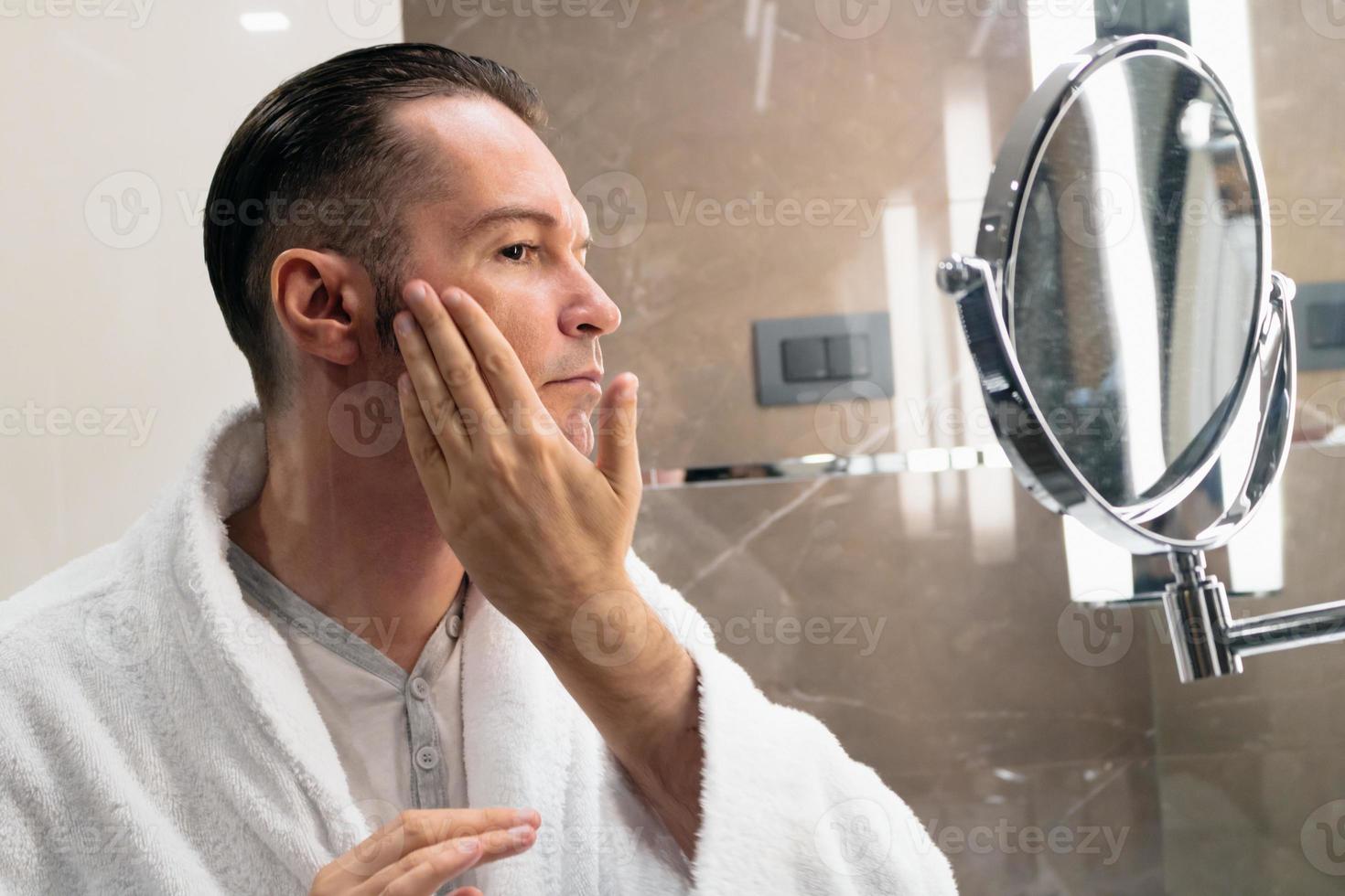 hombre adulto medio aplicando humectante después del afeitado. foto