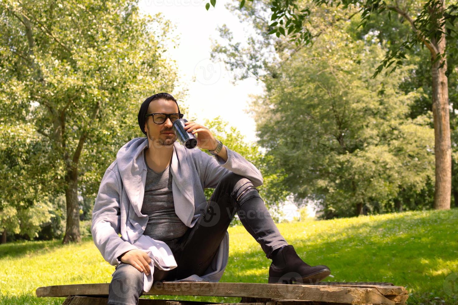 Thoughtful man drinking takeaway coffee while relaxing at the park. photo