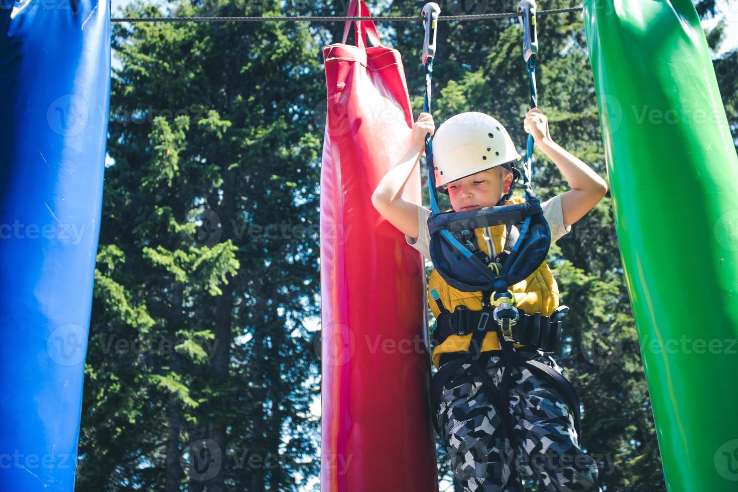 Small boy getting through obstacles in adventure park. photo