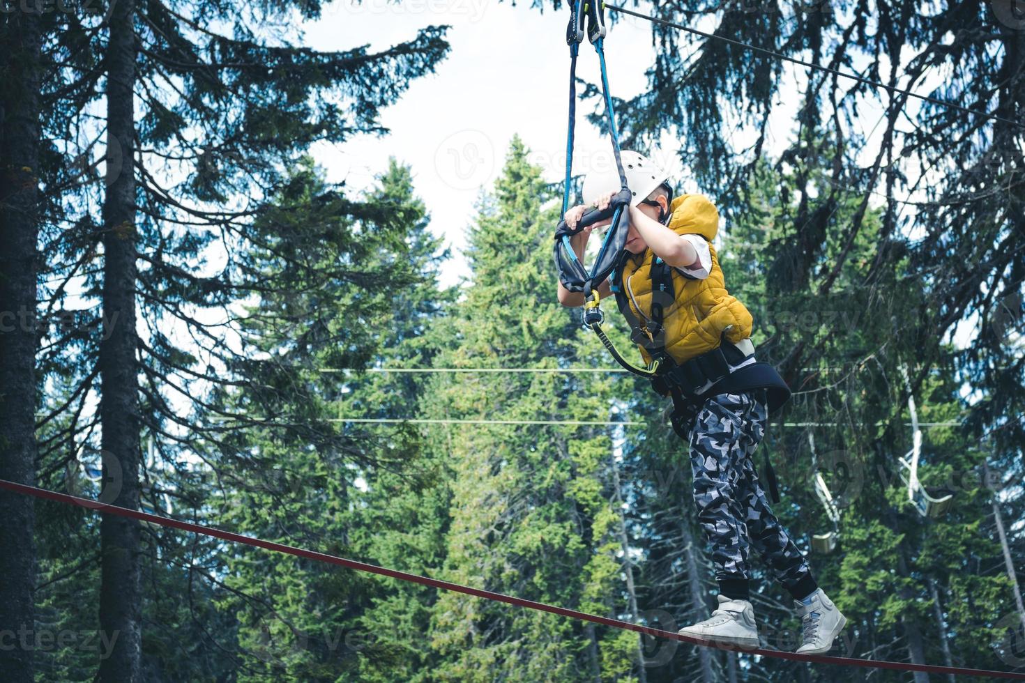 Small boy on rope course in the forest. photo