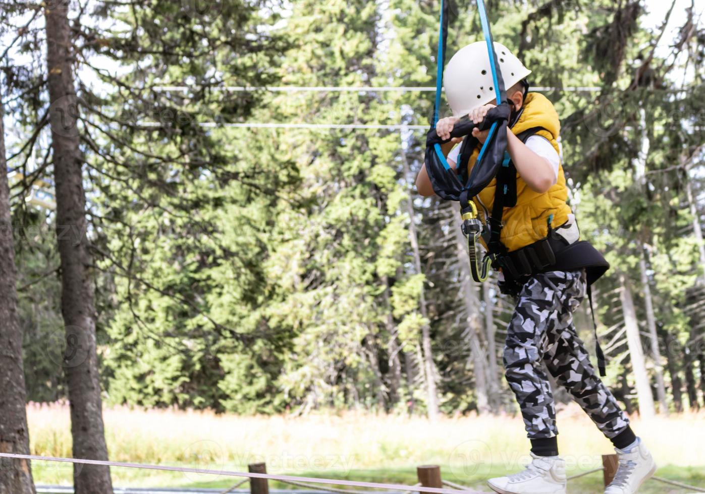 Small boy walking on a rope during canopy tour in nature. photo