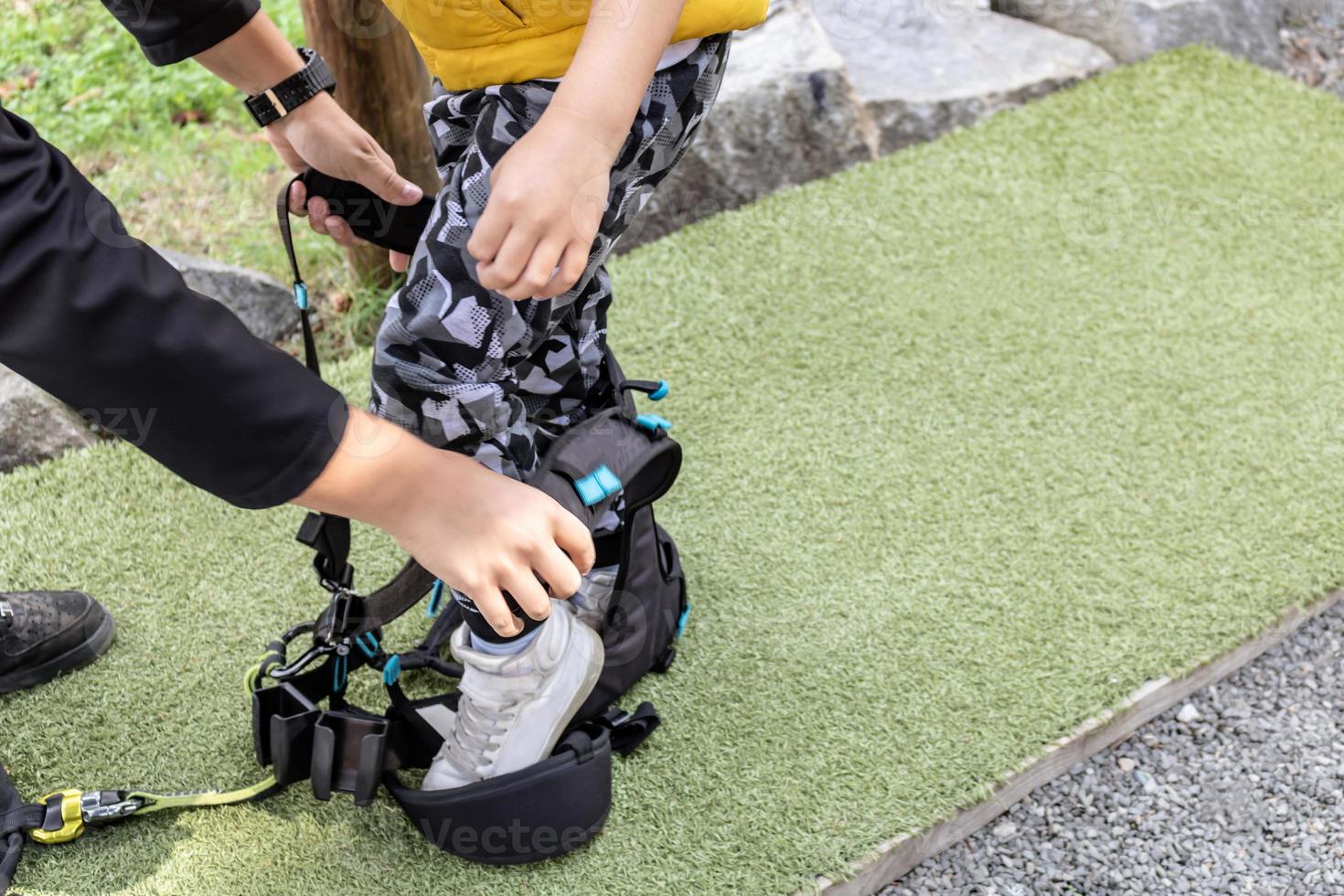 Unrecognizable kid preparing for zip line and dressing on safety harness . photo