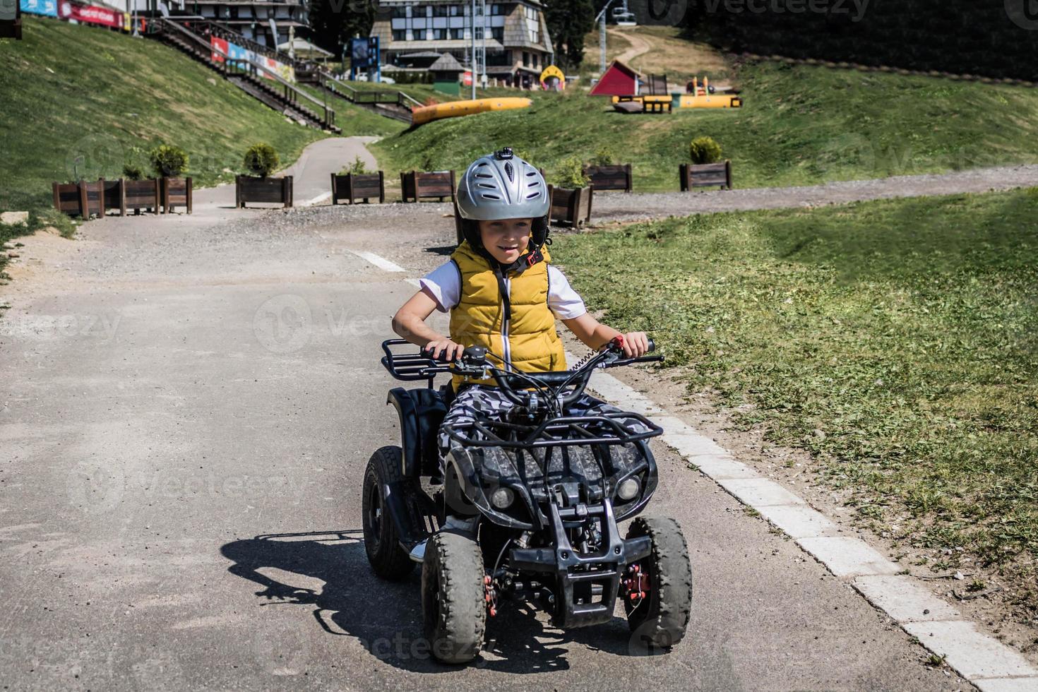 Smiling boy learning to drive quadricycle on a track. photo