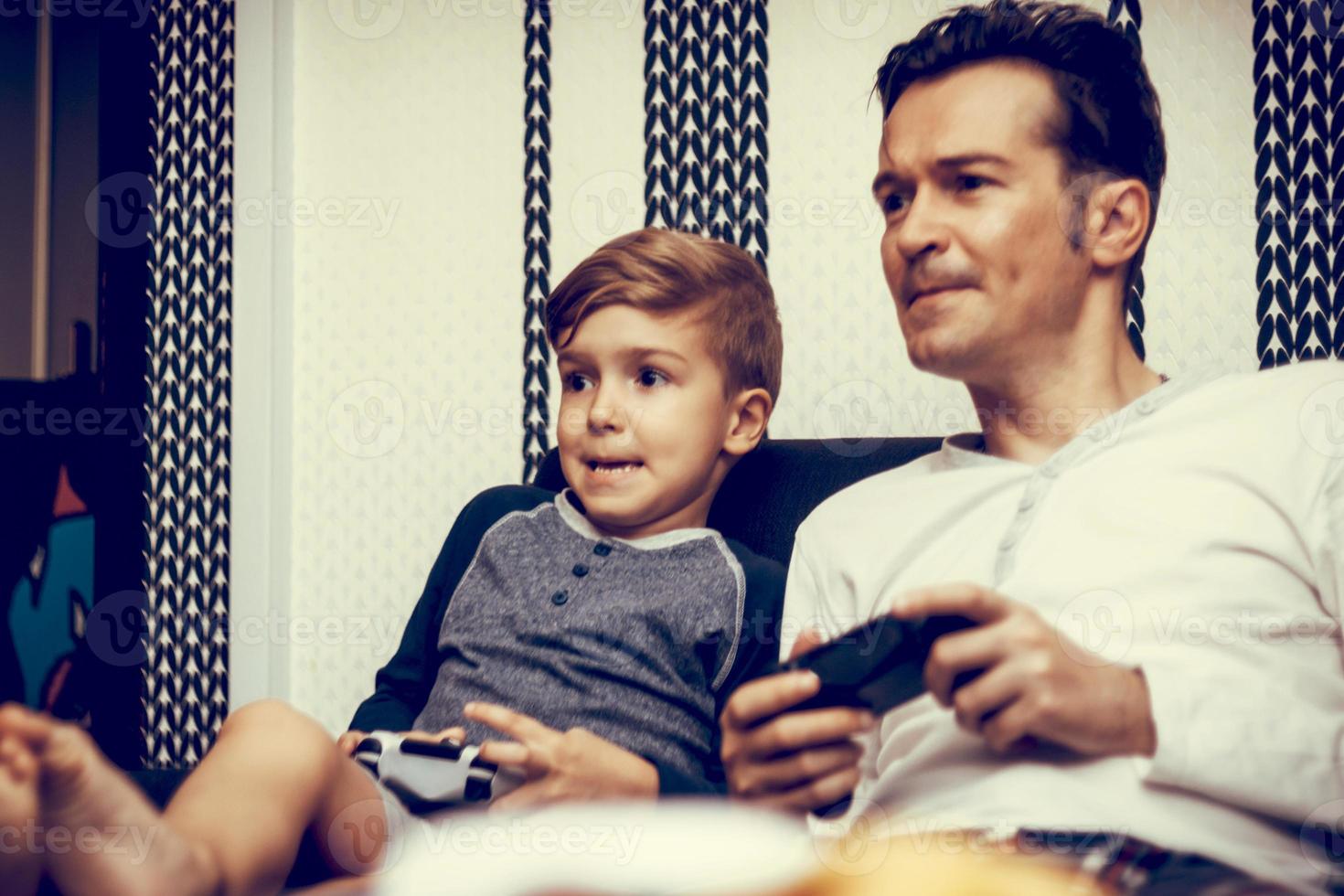 niño pequeño y su padre jugando videojuegos juntos. foto