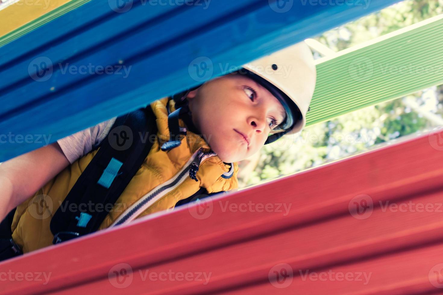 Small kid crawling through obstacle on canopy tour. photo