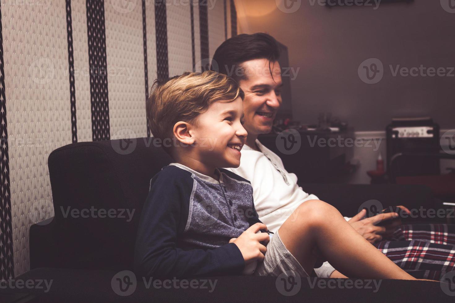 Happy kid enjoying in playing video games with his father. photo