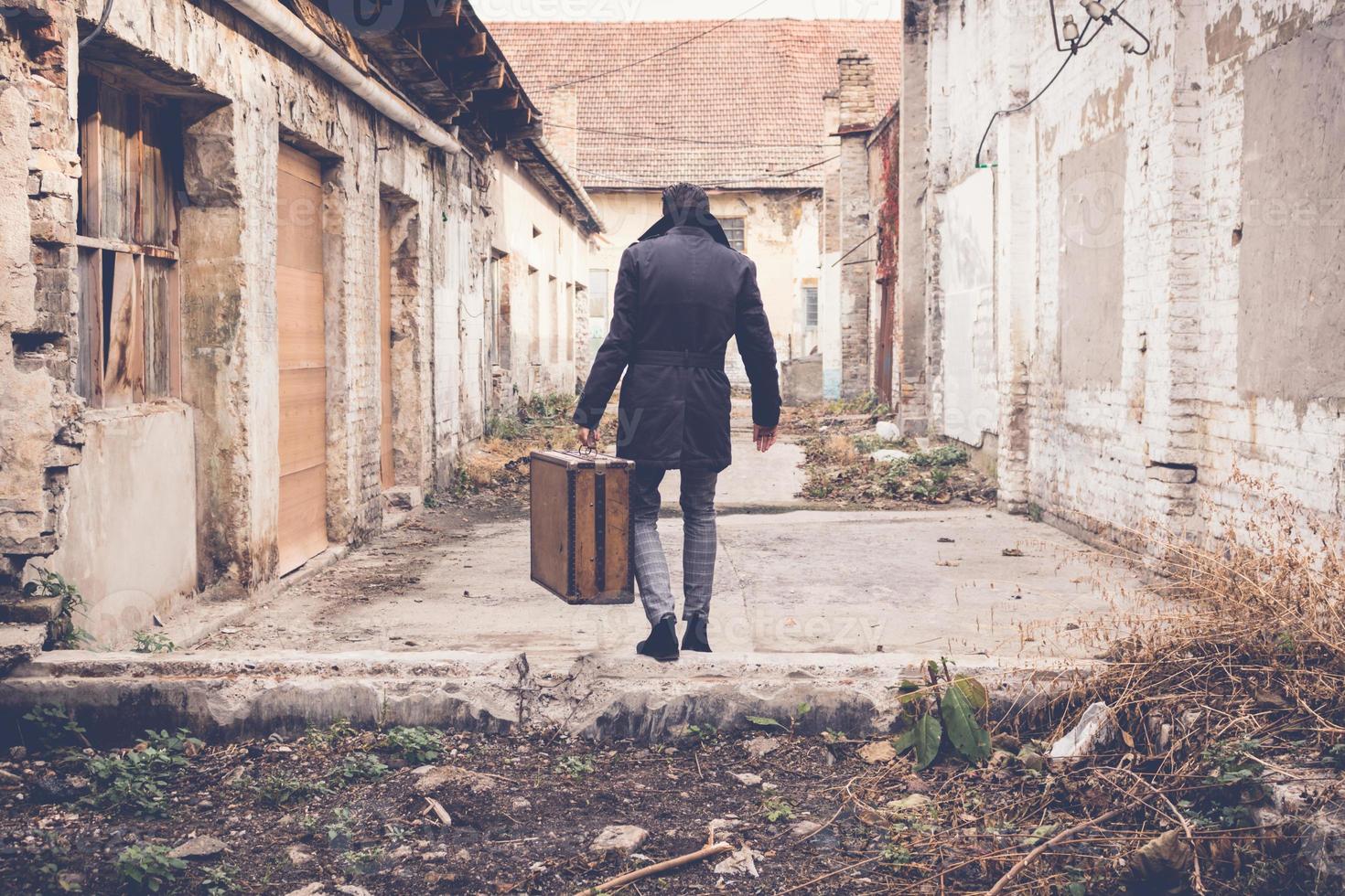 Back view of man carrying suitcase and walking away. photo