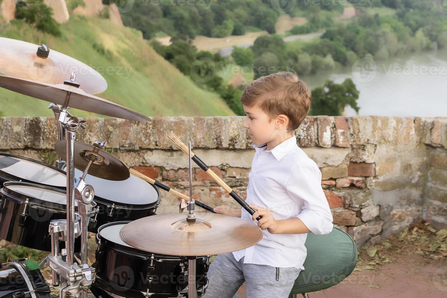 Small kid learning to play drums outdoors. photo
