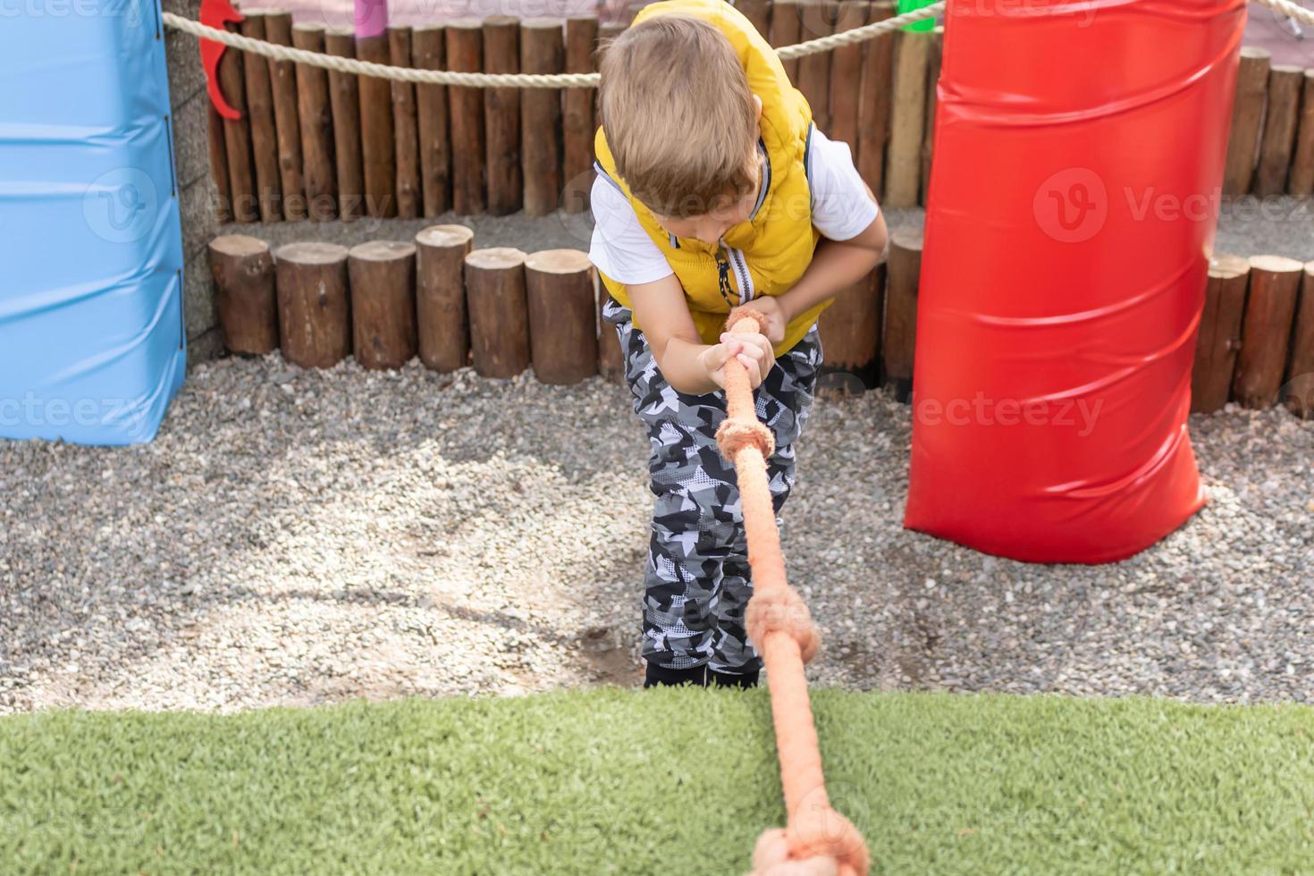Kid pulling rope while climbing up on the playground. photo