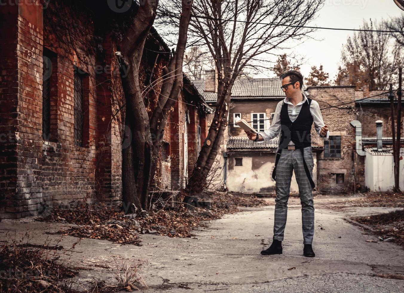 Full length of retro-styled man reading a book outdoors. photo