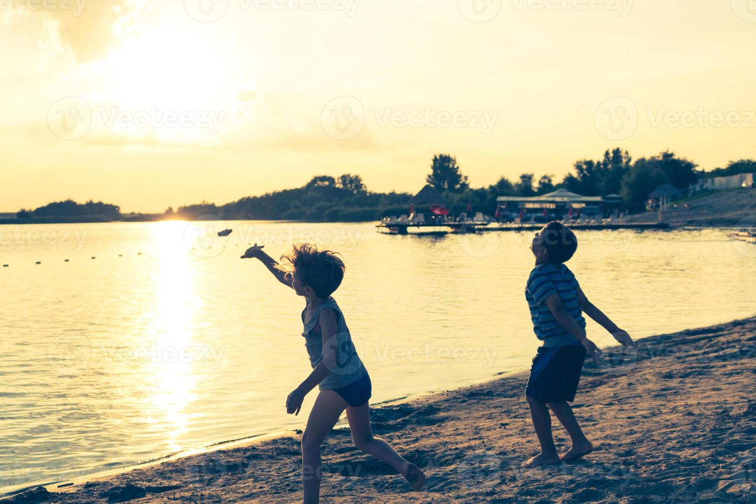 dos niños jugando en la playa al atardecer. foto