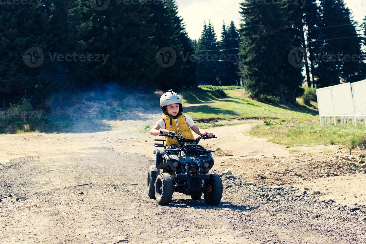 Kid driving quadbike on extreme terrain. photo