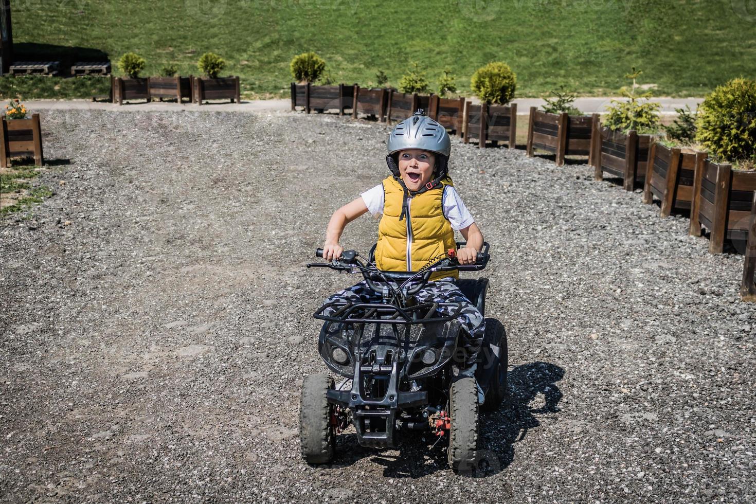 niño pequeño divirtiéndose mientras conduce quads en camino de tierra. foto