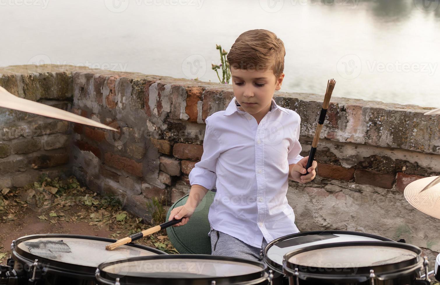 Little boy playing drums outdoors. photo