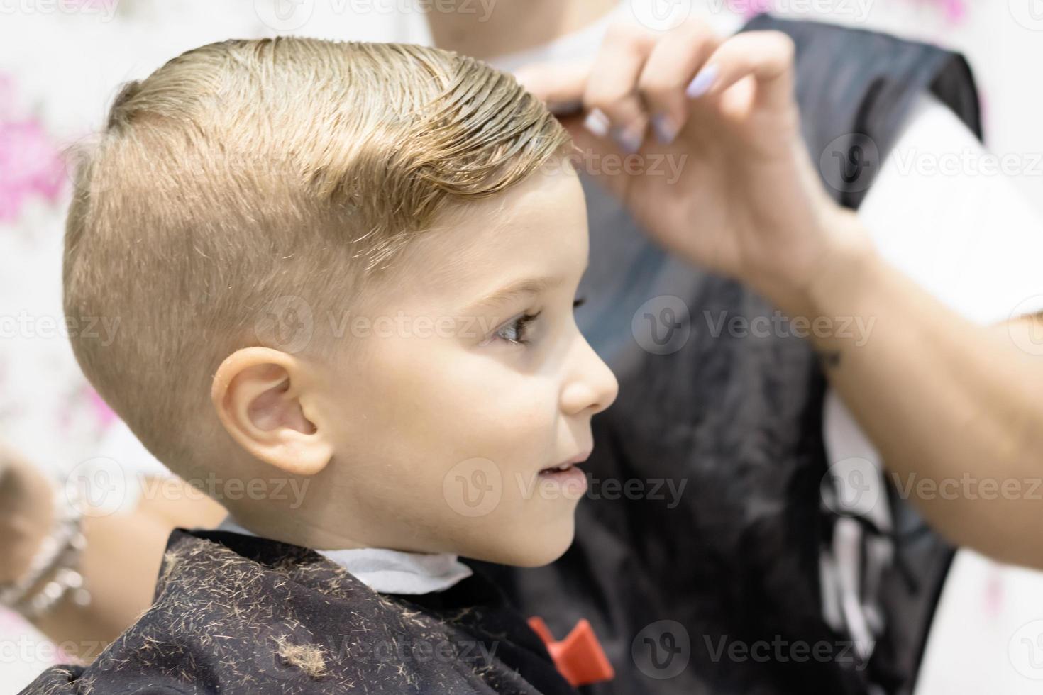 Close up of boy getting a hairstyle at hair salon. photo