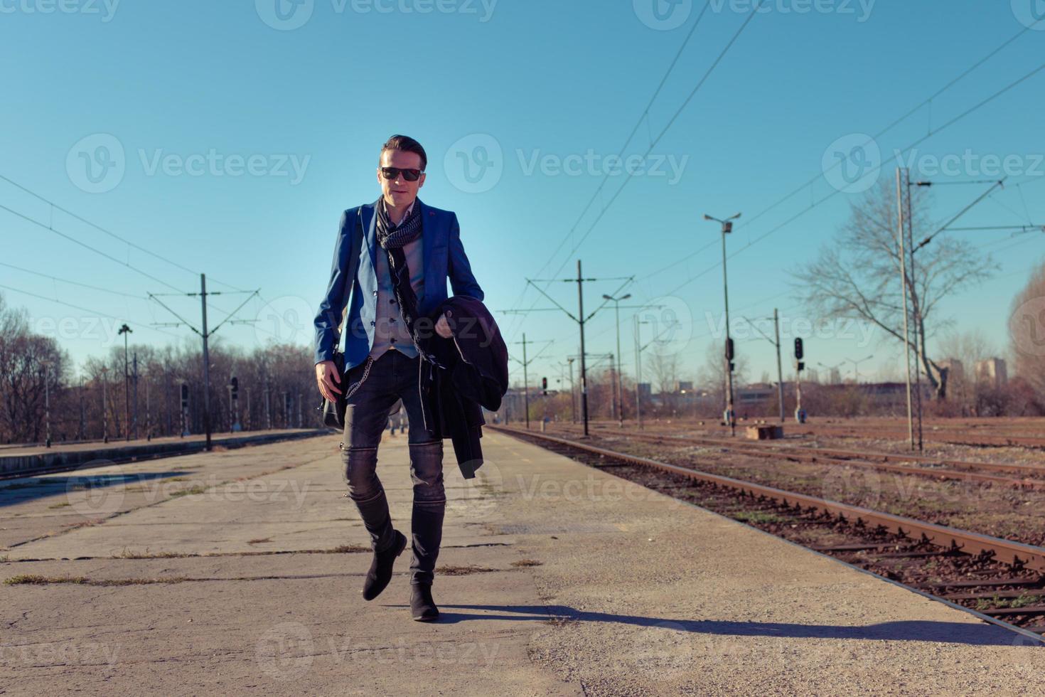 Full length of man walking at railroad station platform. photo